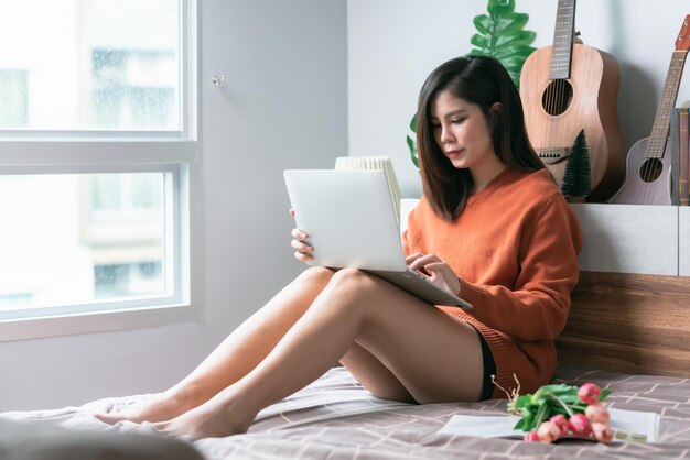Hermosa mujer joven asiática creativa independiente que trabaja en una computadora portátil que trabaja desde el concepto de hogar