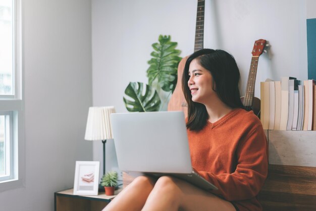 Hermosa mujer joven asiática creativa independiente que trabaja en una computadora portátil que trabaja desde el concepto de hogar