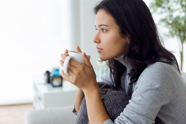 Hermosa mujer joven beber café en casa.