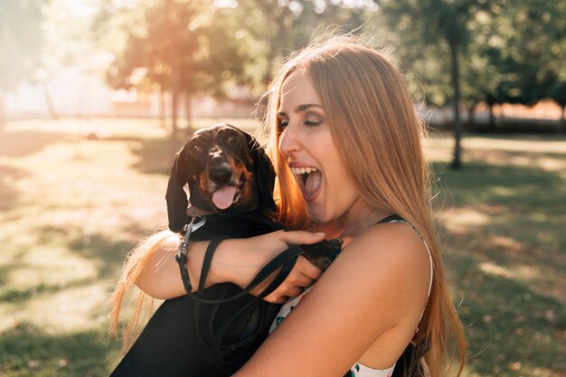 Hermosa mujer joven con la boca abierta amando a su perro