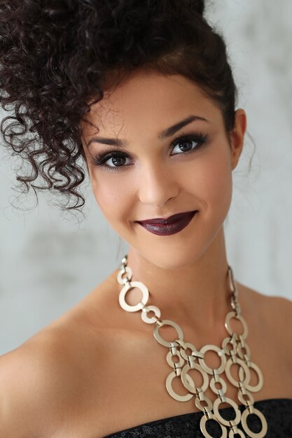 Hermosa mujer joven con cabello rizado negro y vestido negro brillante