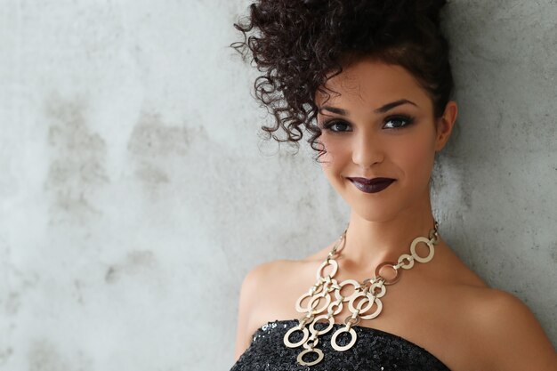 Hermosa mujer joven con cabello rizado negro y vestido negro brillante