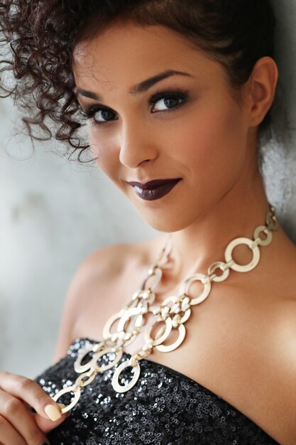 Hermosa mujer joven con cabello rizado negro y vestido negro brillante