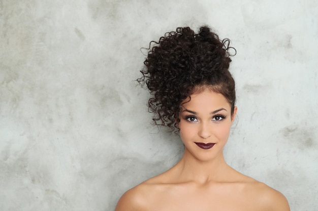 Hermosa mujer joven con cabello rizado negro y vestido negro brillante