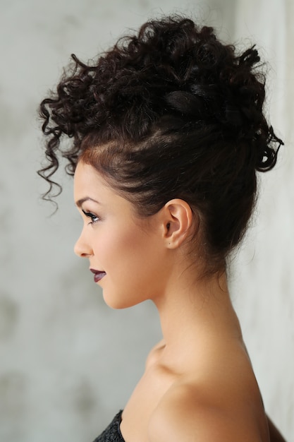 Foto gratuita hermosa mujer joven con cabello rizado negro y vestido negro brillante