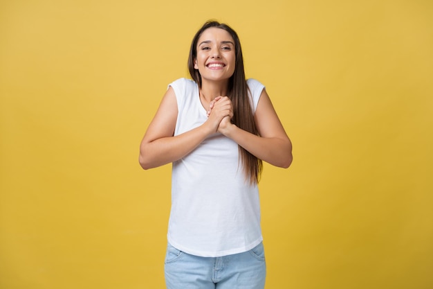 Hermosa mujer joven con camisa blanca sostiene la cabeza en las manos sonriendo y mirando a la cámara