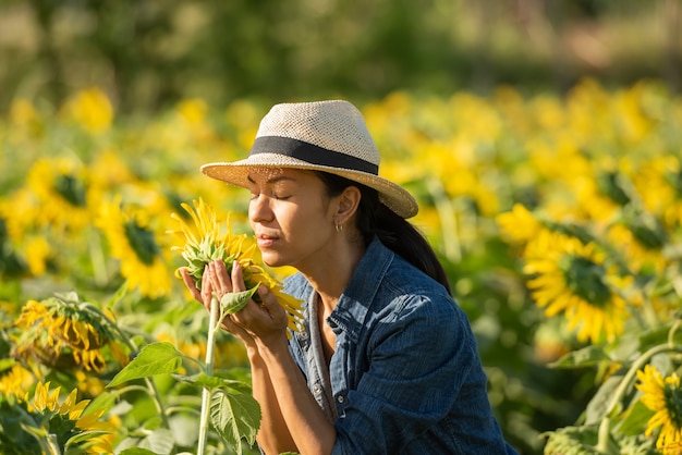 Hermosa mujer joven en un campo de girasoles con un vestido blanco. viajar en el concepto de fin de semana. retrato de mujer auténtica con sombrero de paja. Al aire libre en el campo de girasoles.