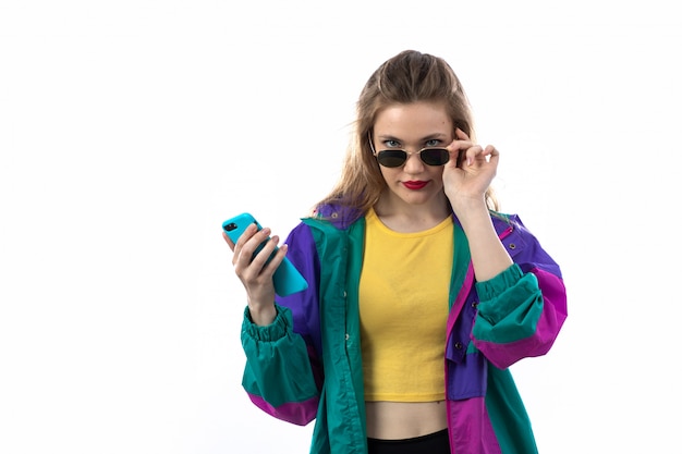 Hermosa mujer joven en chaqueta colorida y gafas de sol con smartphone