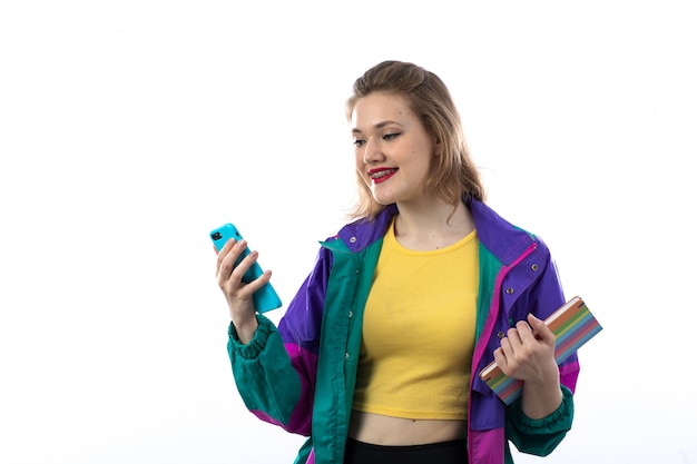 Hermosa mujer joven en chaqueta colorida con smartphone y libro de explotación