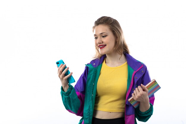 Hermosa mujer joven en chaqueta colorida con smartphone y libro de explotación