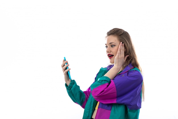 Foto gratuita hermosa mujer joven en chaqueta colorida con smartphone