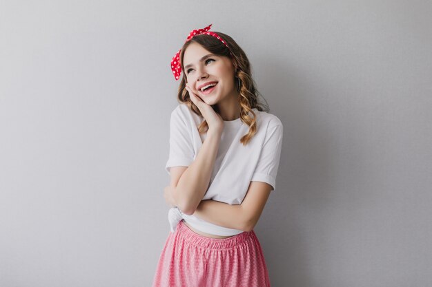 Hermosa mujer joven con cinta roja posando de ensueño. Señora despreocupada con linda sonrisa de pie.