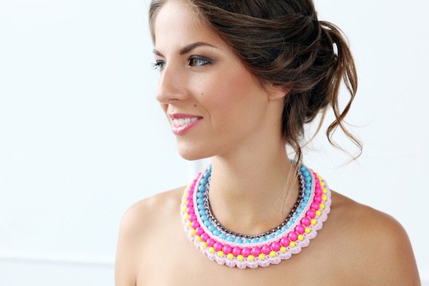 Foto gratuita hermosa mujer joven con collar colorido y sonriente