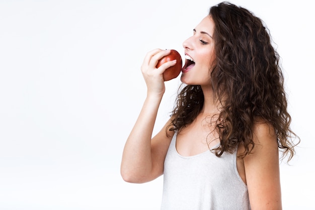 Foto gratuita hermosa mujer joven comer manzana roja sobre fondo blanco.