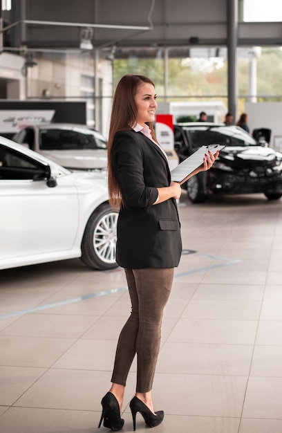 Foto gratuita hermosa mujer joven en concesionario de automóviles