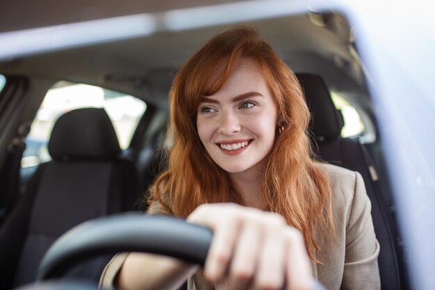 Hermosa mujer joven conduciendo su auto nuevo al atardecer