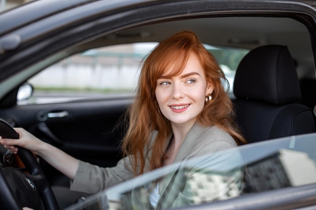 Hermosa mujer joven conduciendo su auto nuevo al atardecer