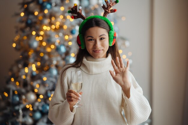 Hermosa mujer joven con copa de champán en casa. celebración de Navidad