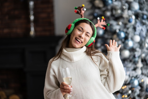 Hermosa mujer joven con copa de champán en casa. celebración de Navidad