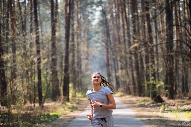 Hermosa mujer joven corriendo en el parque verde en un día soleado de verano