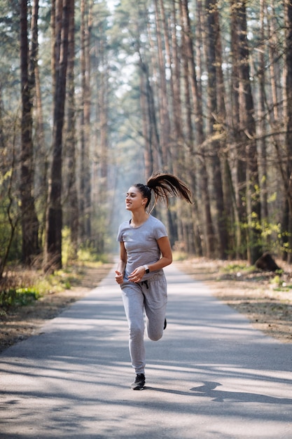 Foto gratuita hermosa mujer joven corriendo en el parque verde en un día soleado de verano