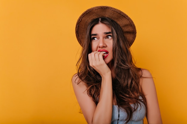 Hermosa mujer joven con expresión de la cara preocupada de pie en el espacio naranja