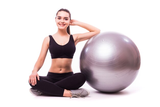 Hermosa mujer joven fitness con ejercicio de pelota de gimnasia, aislado sobre fondo blanco.