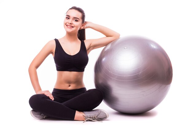 Hermosa mujer joven fitness con ejercicio de pelota de gimnasia, aislado sobre fondo blanco.