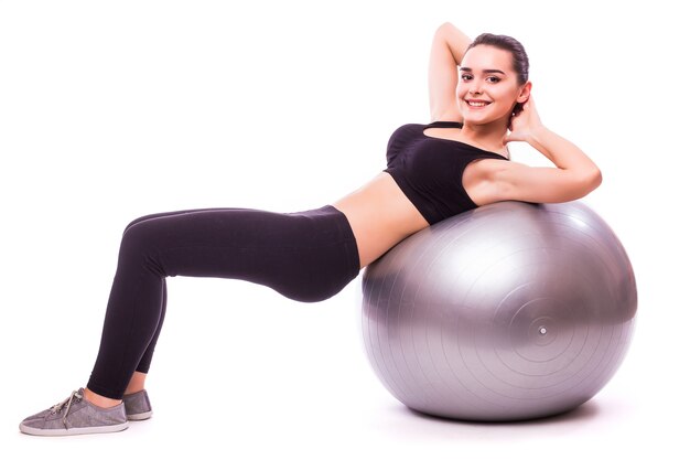 Hermosa mujer joven fitness con ejercicio de pelota de gimnasia, aislado sobre fondo blanco.