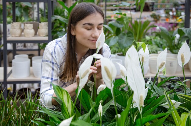 Hermosa mujer joven en una floristería y elegir flores.