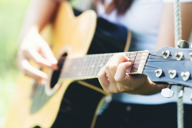 Hermosa mujer joven con guitarra acústica en la naturaleza