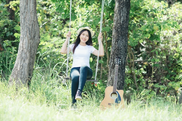 Hermosa mujer joven con guitarra acústica en la naturaleza