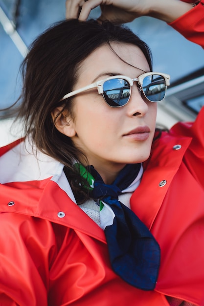 Hermosa mujer joven en un impermeable rojo monta un yate privado. Estocolmo, Suiza