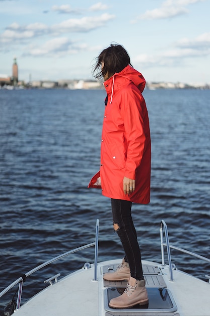 Hermosa mujer joven en un impermeable rojo monta un yate privado. Estocolmo, Suiza