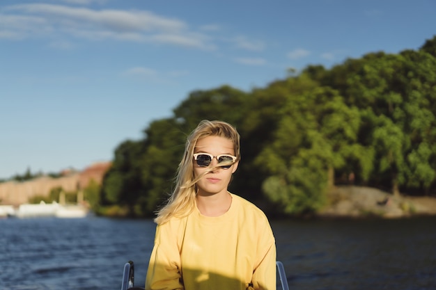 Hermosa mujer joven en un impermeable rojo monta un yate privado. Estocolmo, Suiza