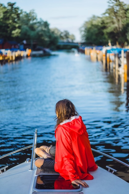 Hermosa mujer joven en un impermeable rojo monta un yate privado. Estocolmo, Suiza