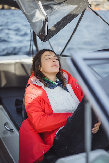 Hermosa mujer joven en un impermeable rojo monta un yate privado. Estocolmo, Suiza