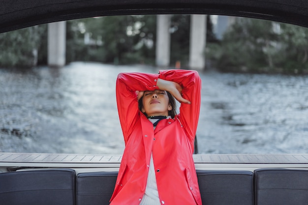 Foto gratuita hermosa mujer joven en un impermeable rojo monta un yate privado. estocolmo, suiza