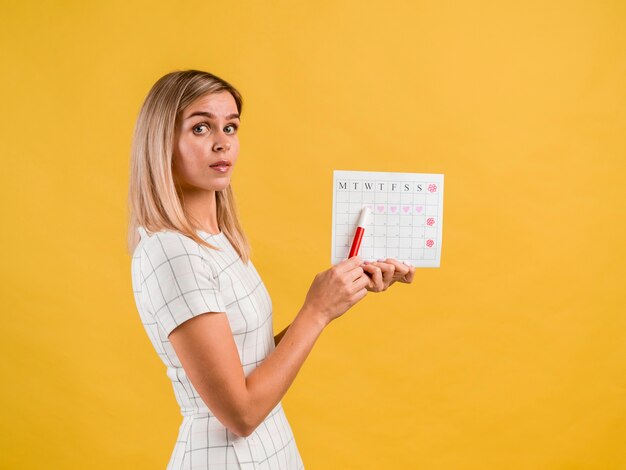 Hermosa mujer joven de lado con calendario de espectáculo de sombrero