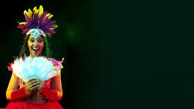 Hermosa mujer joven en máscara de carnaval, elegante traje de mascarada con plumas y bengalas que invitan.