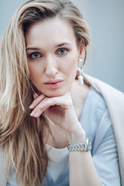 Hermosa mujer joven con pelo largo ondulado y aretes de joyería. Belleza natural de la mujer, suavemente maquillaje y cosmética.