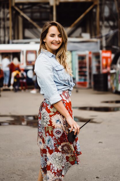 Una hermosa mujer joven con el pelo largo con un vaso de café está sonriendo y riendo.