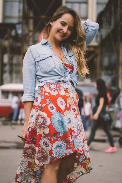 Una hermosa mujer joven con el pelo largo con un vaso de café está sonriendo y riendo.