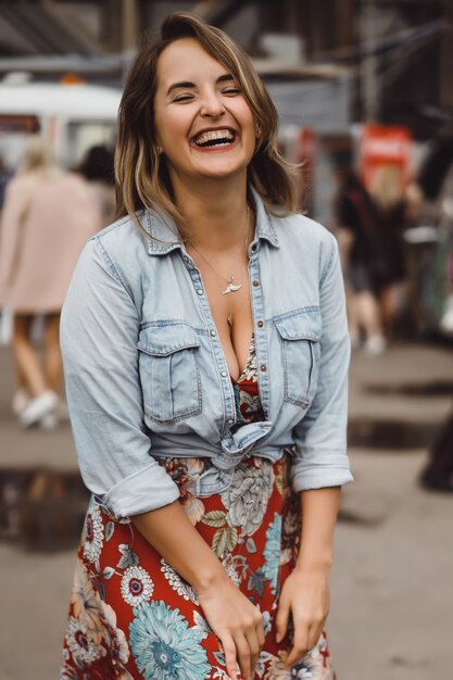 Una hermosa mujer joven con el pelo largo con un vaso de café está sonriendo y riendo.