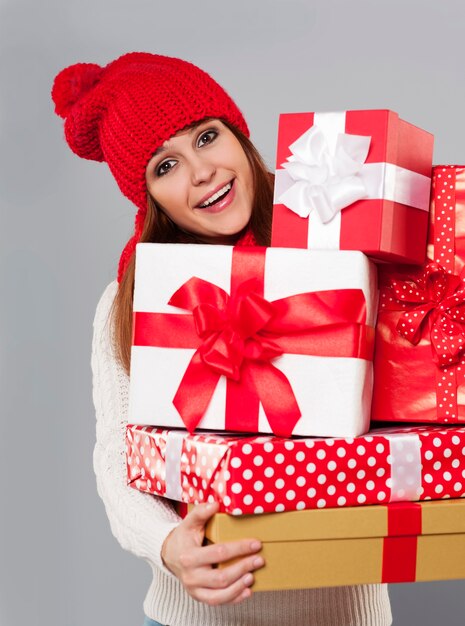 Hermosa mujer joven con pila de regalos de Navidad