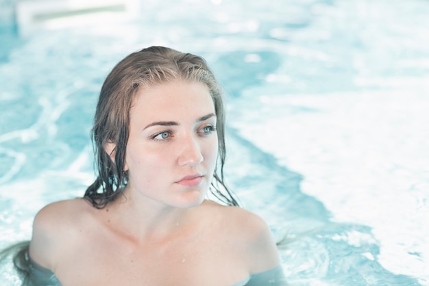 Hermosa mujer joven en la piscina azul