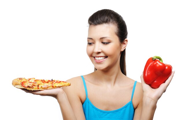 Hermosa mujer joven con pizza en una mano y pimiento rojo en la otra