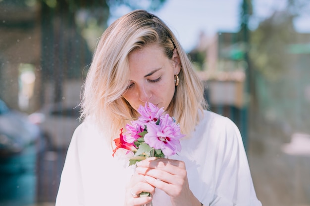 Foto gratuita hermosa mujer joven que huele las flores