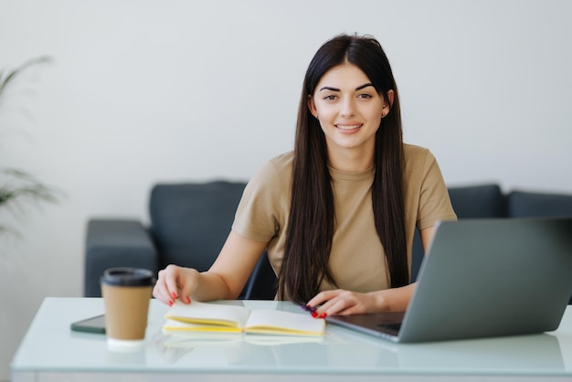 Foto gratuita hermosa mujer joven que trabaja con computadora portátil concentrada y sonriente en la oficina en casa