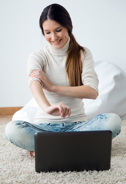 Hermosa mujer joven que trabaja en su computadora portátil en casa.